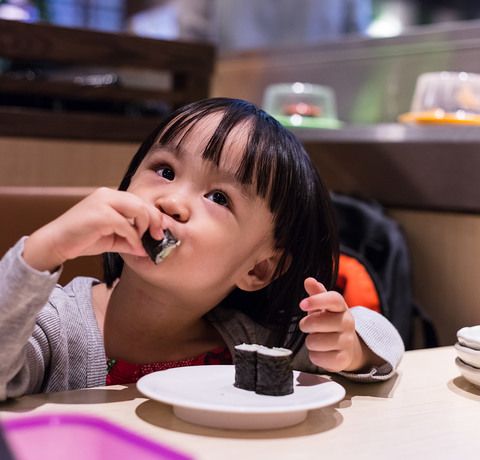 Japońska dziewczynka je sushi w restauracji
